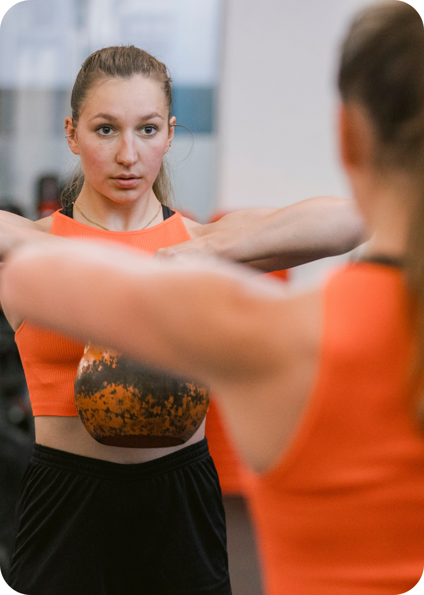 Woman looking in the mirror pulling a kettlebell.